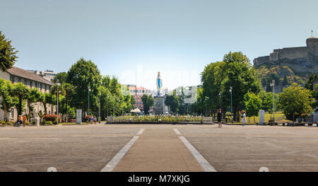 Lourdes, France - June 22, 2017 : view of the esplanade in front of the basilica of Lourdes with a statue of the Virgin Mary crowned on a summer day Stock Photo