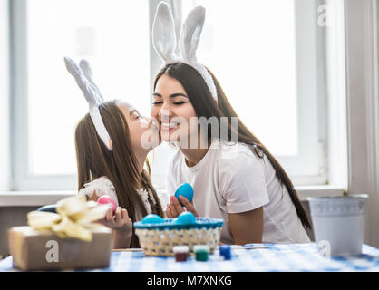 Family celebrating Easter. mother and daughter kissing at home with decorations multi colored eggs Stock Photo