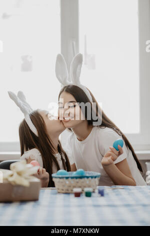 Mother and daughter together at home easter preparation in bunny ears sitting girl kissing mom Stock Photo