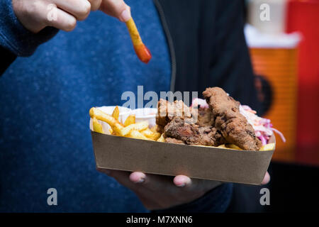 Man dipping chip in ketchup on takeaway tray. Stock Photo