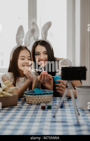 Mother and daughter making selfie while decorating Easter eggs in the kitchen Stock Photo