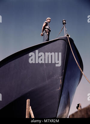 Coast Guard Sentry Standing Watch over New Torpedo Boat Under Constructions at Shipyard, Higgins Industries, Inc., New Orleans, Louisiana, USA, Howard R. Hollem for Office of War Information, July 1942 Stock Photo