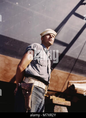 Coast Guard Sentry Standing Watch over New Torpedo Boat Under Constructions at Shipyard, Higgins Industries, Inc., New Orleans, Louisiana, USA, Howard R. Hollem for Office of War Information, July 1942 Stock Photo