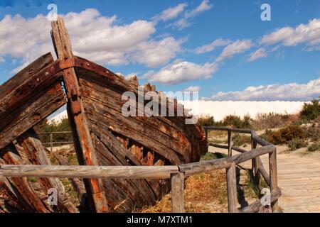 Old abandoned boat on the beach in Santa Pola. Salinas in the background under blue sky Stock Photo