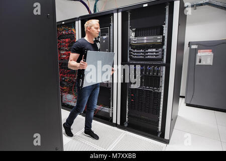 Computer Engineer Carrying Blade Server While Walking In Datacen Stock Photo