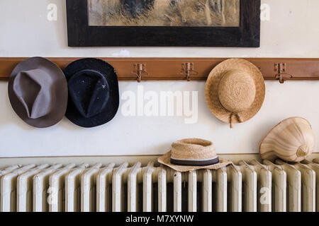 Wall hanger with various hats on it, radiator and old painting Stock Photo