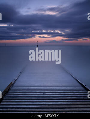 Wooden post silhouette and jetty in the sea at dawn at Llandudno, North Wales coast Stock Photo
