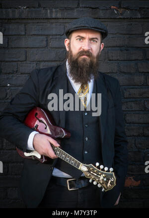 A bearded man standing with a mandolin. Stock Photo