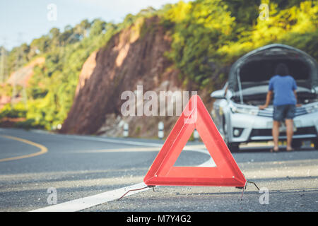 Asian woman using smartphone in front of her broken car on the road. Contacting car technician or need help concept Stock Photo