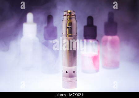 Electronic cigarette  with five e-liquid in the white smoke on a dark background. E-juice from vape. Alternative to smoking Stock Photo