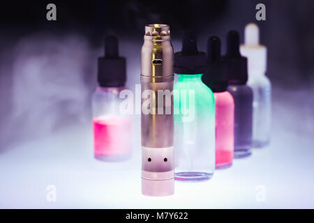 Electronic cigarette  with five e-liquid in the white smoke on a dark background. E-juice from vape. Alternative to smoking Stock Photo