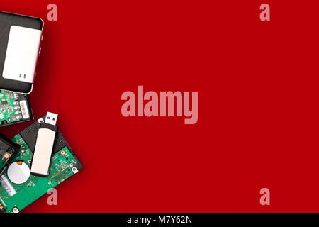 Hard drives and flash drive on the side of the frame on a red background. Top view with space for your text. Computer storage concept. Stock Photo