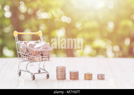 Close up hand putting coins in stack on wooden plank. savings concept. Stock Photo