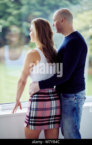 Couple stood looking out of window Stock Photo