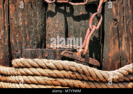 Closeup of coiled rope and rusty chain on a pier. Stock Photo