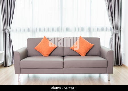 Grey sofa in modern living room beside the window. Home interior decoration Stock Photo