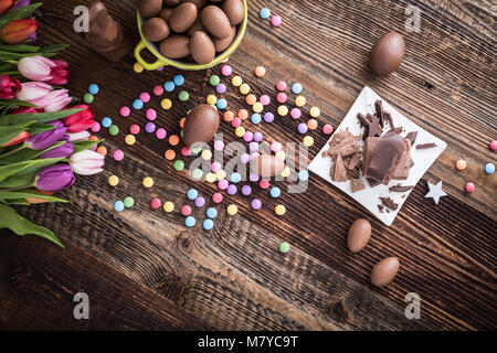 Easter wooden background with chocolate easter eggs, dragee and tulips Stock Photo