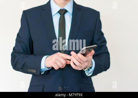 Intelligent and confidents businessman holding phone in hand. taping touch screen. closeup Stock Photo