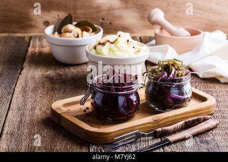 Healthy vegetarian meal. Mashed potatoes and homemade pickled mushrooms. Sea kale salad with red onion and beetroot salad on rustic wooden table Stock Photo