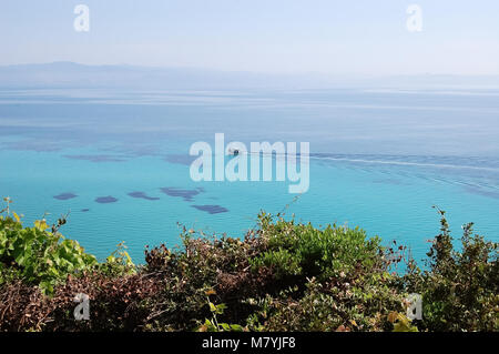 View from the shore to the floating boat and turquoise cleanest sea in Greece. Stock Photo