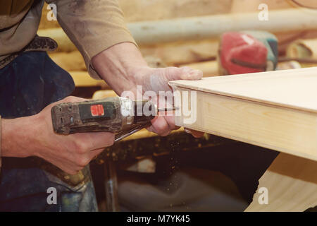 Carpenter's Hands Man Worker Drilling Wood at Construction Site. Stock Photo