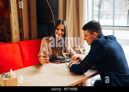 Young happy couple romantic date drink glass of white wine at restaurant, celebrating valentine day Stock Photo