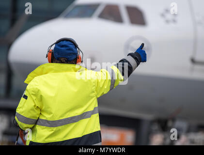 08 March 2018, Germany, Frankfurt: Sabrina Boock, in charge of ground handling operations, gives the 'all clear' to the cockpit of an Airbus A 321 passenger aircraft at Frankfurt airport. On the occasion of the International Women's Day all operational positions of Lufthansa flight LH 174 including cabin crew, cockpit and on the apron are staffed with women. The only exception is the loading of luggage and shipment, which is still staffed by men due to health and safety workplace regulations. Photo: Fabian Sommer/dpa