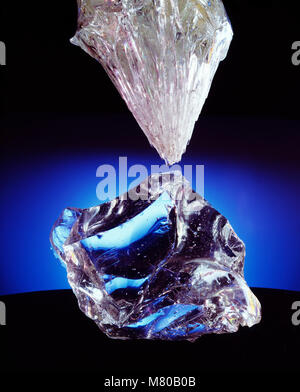 Two specimens of glass cuttle,  one of which has cooled into a cone of fine crystals and one has become a solid shape including smooth surfaces. Stock Photo
