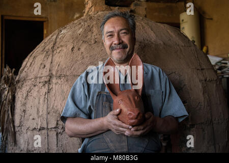 Ceramic artist Nicholas Fabian holds a traditional Purepecha design ceramic mask in front of his kiln in Santa Fe de la Laguna, Michoacan, Mexico. Stock Photo