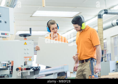 Carpenter in furniture factory inspecting piece in QA Stock Photo