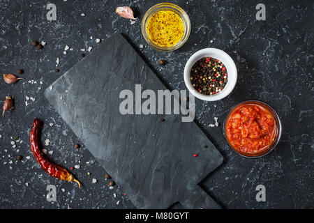 Black slate board, mustard, sauce and spices. Cooking or food background Stock Photo