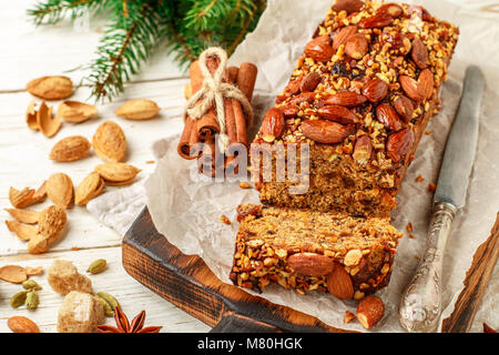 Festive Homemade Holiday Fruitcake with Nuts, Fruit and spices. Almonds, cinnamon, star anise, cardamom on the table. Christmas. New year. Selective f Stock Photo