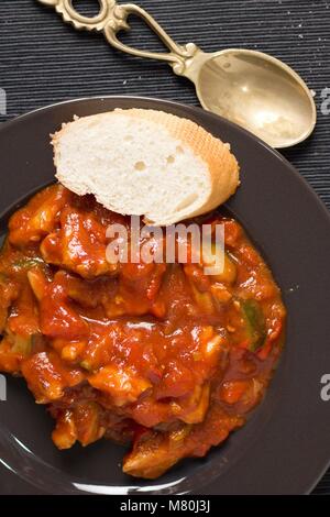 Directly above shot of red vegetable stew or ragout dish served on black plate with bread Stock Photo