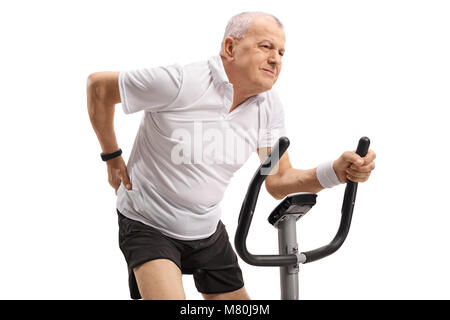 Mature man riding an exercise bike and experiencing back pain isolated on white background Stock Photo