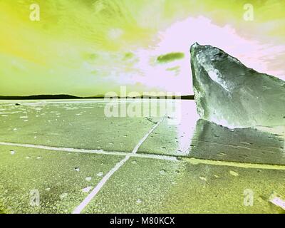 Beautiful epic ice crystal in the frozen bay.  Sun rays reflection in cracks, backlight  of the setting sun. Stock Photo