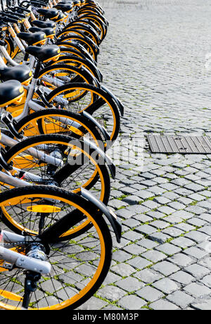 Many bicycle for rent parked in a row on urban sidewalk city street Stock Photo