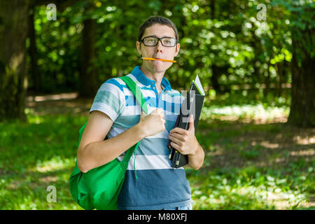 Photo of student with pencil in mouth, glasses Stock Photo
