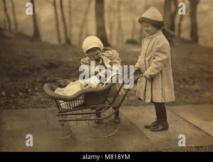 Two Young Girls Playing with Doll in Carriage, New York City, New York, USA, Lewis Hine for National Child Labor Committee, March 1912 Stock Photo