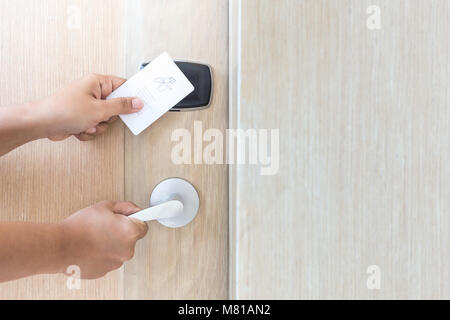 Close up hand holding white hotel key card in front of electric door Stock Photo