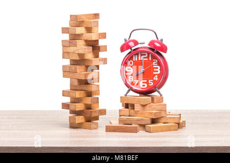 Pile of blocks wood game and red alarm clock on wooden table. Studio shot and isolated on white background Stock Photo