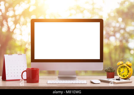 Modern desktop computer, Coffee cup, alarm clock, notebook and calendar on wooden table and abstract light blur and bokeh background. Saved with clipp Stock Photo