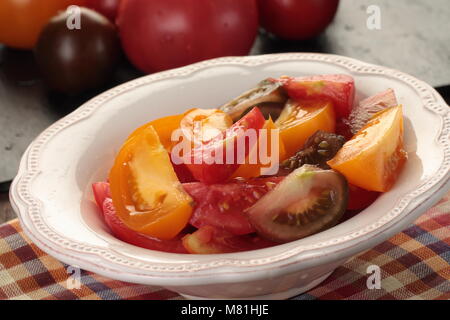 Sliced tomatoes in a bowl on a rustic table Stock Photo