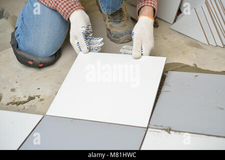 Worker installs ceramic tiles on a floor Stock Photo