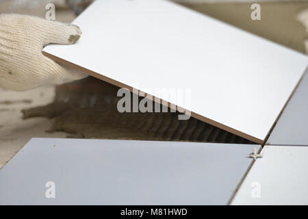 Worker installs ceramic tiles on a floor Stock Photo