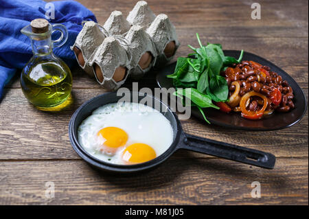 The pan fried eggs, haricot stewed in tomato sauce and fresh spinach. Concept of a healthy breakfast. Stock Photo
