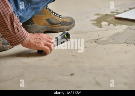 Worker checking the surface using spirit level during the tiled floor installation Stock Photo