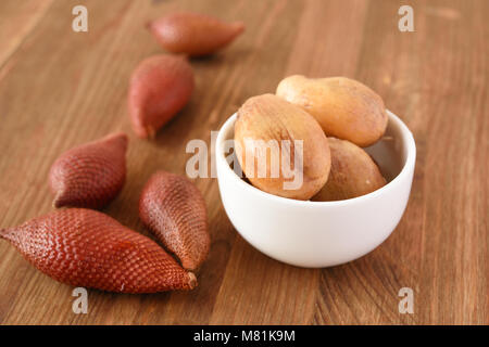 Peeled and unpeeled salak fruits also known as snake fruits on a table Stock Photo