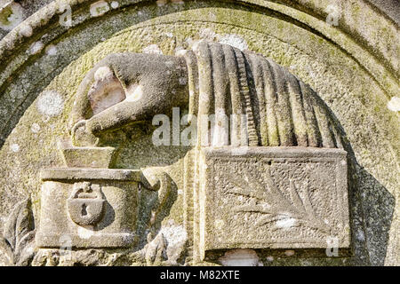 The headstone of a charitable man shows a hand dropping a coin into a traditional tzedakah box for charity in the Okapawa Street Jewish Cemetery in Wa Stock Photo