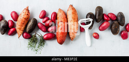 cleaning and cooking of different types of potatoes, spices and a knife on the table Stock Photo
