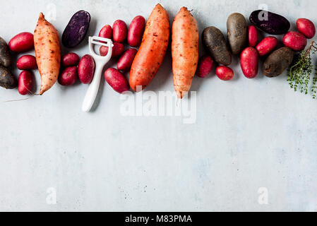 cleaning and cooking of different types of potatoes, spices and a knife on the table Stock Photo